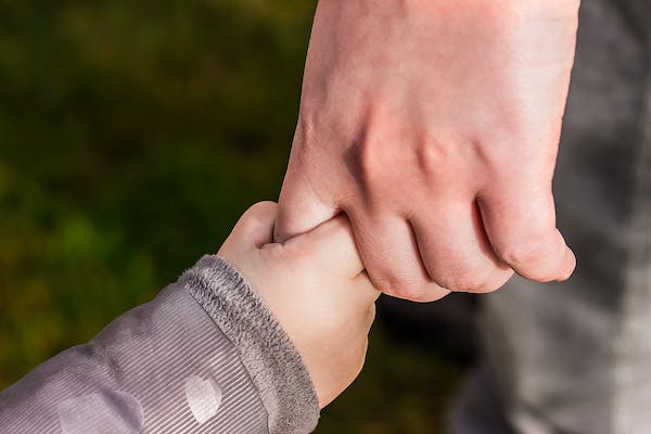 Vater hält Hand seines Kindes